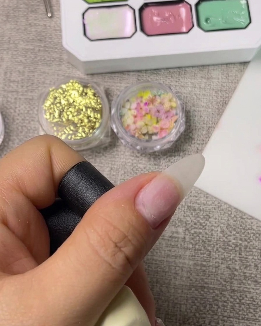 Nahaufnahme eines Pinsels beim Auftragen eines klaren Base Coats auf einen sauberen Naturnagel.