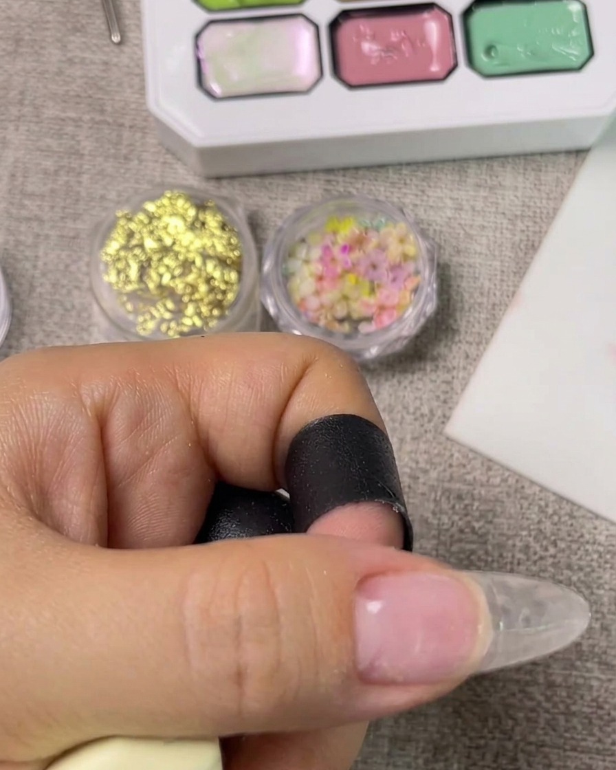 Eine Hand in einer UV-Nagellampe bei aktiviertem Licht, um den Base Coat auszuhärten.