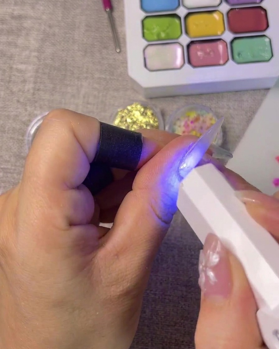 Ein French-Tip-Sticker wird präzise auf die Spitze eines Fingernagels platziert.