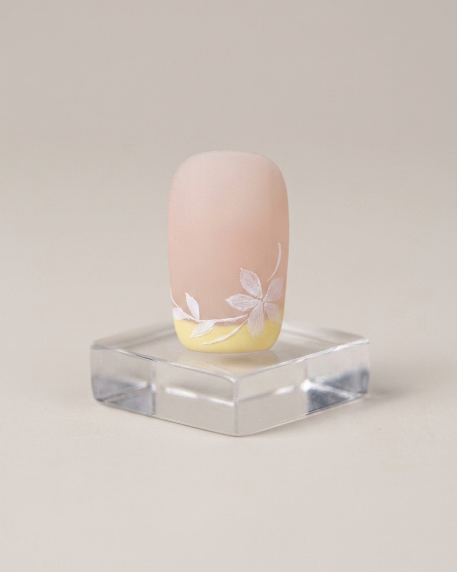 Ein Pinsel trägt eine gleichmäßige Schicht hellen Nude-Gel-Basislacks auf einen Naturnagel auf.