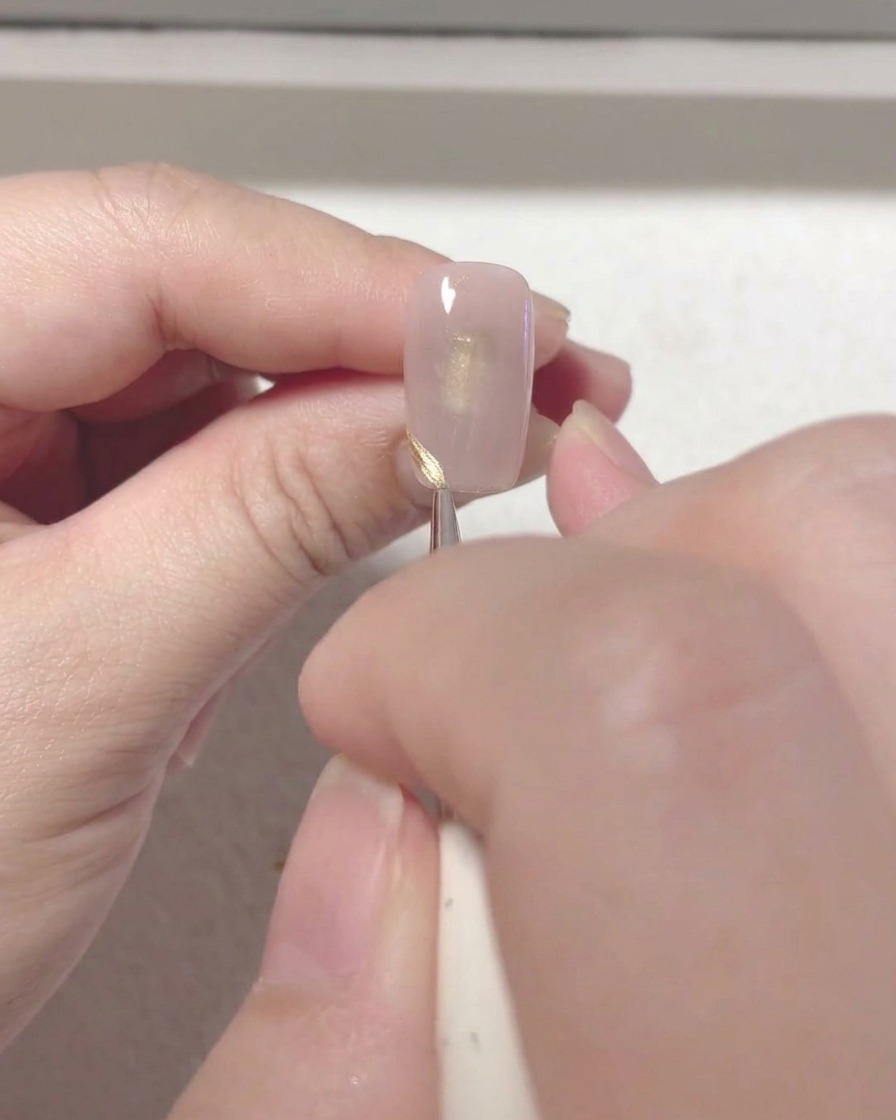 Ein dünner Nailart-Pinsel zeichnet eine saubere, rote French-Tip-Linie am Nagelrand.
