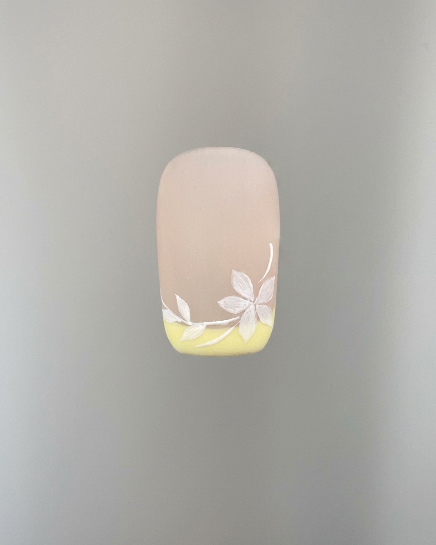 Eine Detailaufnahme zeigt, wie weitere weiße Sakura-Blütenblätter zur Nailart hinzugefügt werden.