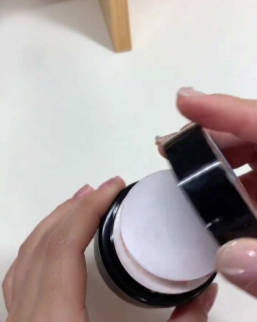 Ein Pinsel trägt eine ebenmäßige Schicht nudefarbenes Gel auf eine Nagelverlängerung auf.