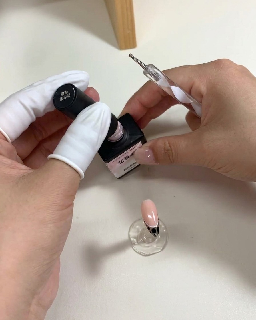 Ein Dotting-Tool platziert fünf pinke Gelpunkte in Blütenform auf den Nagel.