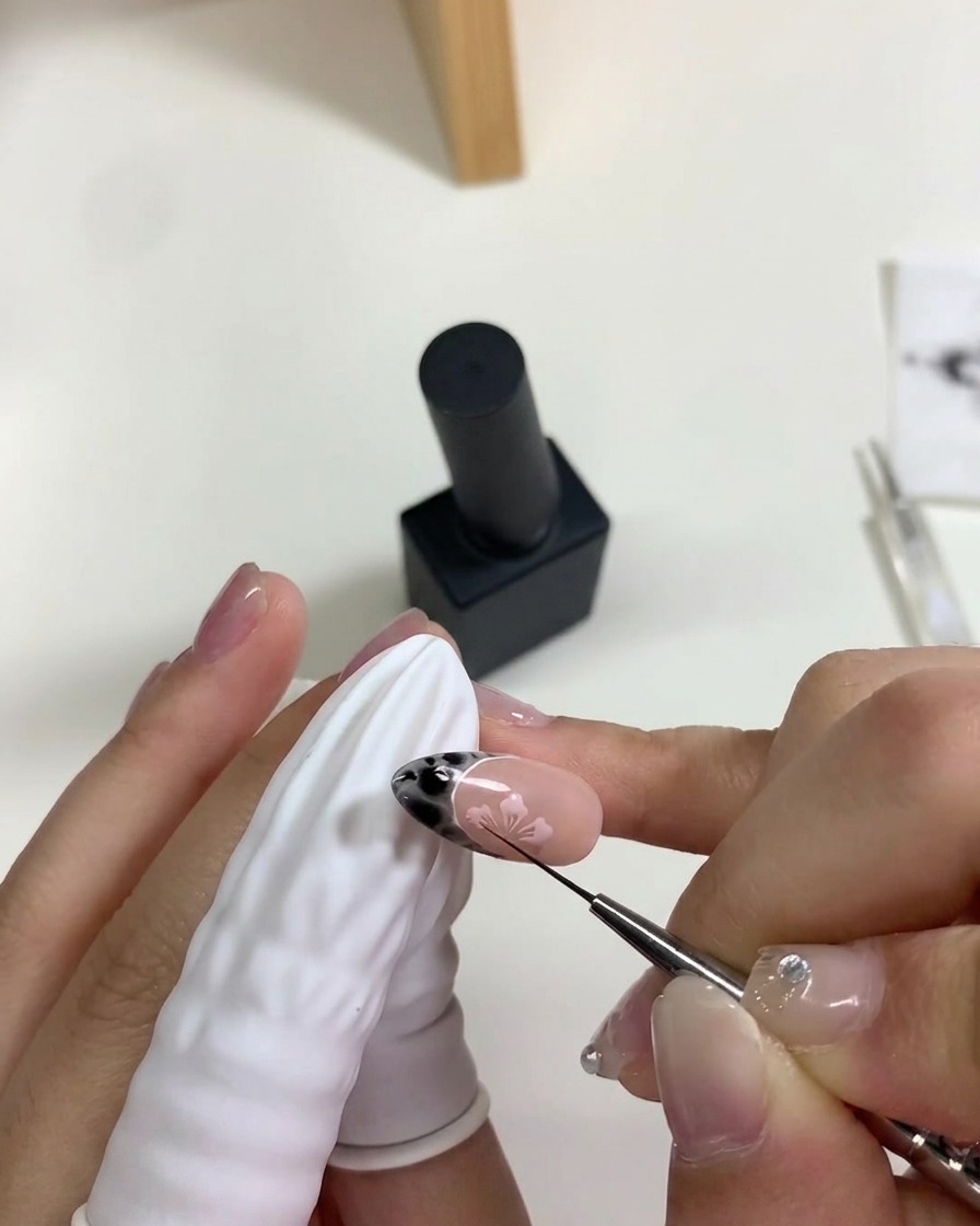 Eine Hand legt den Nagel unter eine mobile Mini-UV/LED-Lampe, um die pinke Kirschblüten-Kunst auszuhärten.