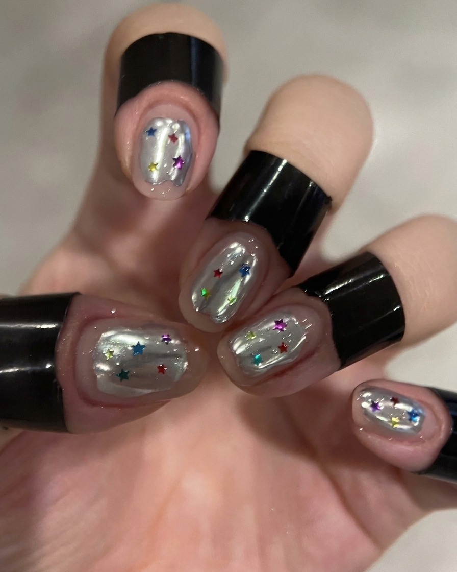 Ein kleiner Schwamm entfernt überschüssiges silbernes Chrom-Puder von einem Nagel.