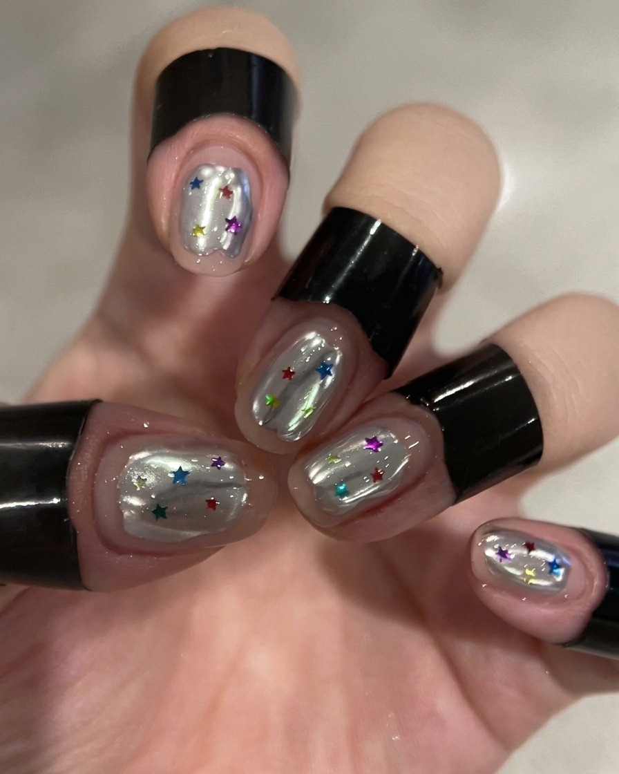 Ein Pinsel trägt einen klaren Top Coat über einen silbernen Chrome-Nagel auf.