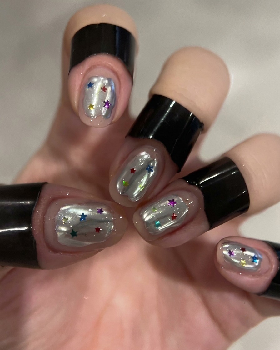 Ein Dotting-Tool platziert bunte Stern-Pailletten auf das Aufbaugel eines Nagels.