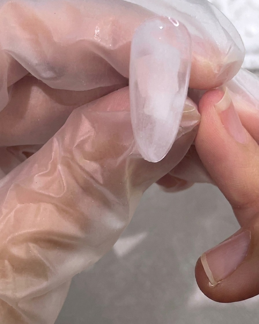 Ein Pinsel verblendet das weiße Gel mit der klaren Basis zu einem sanften, wolkigen Marmoreffekt.