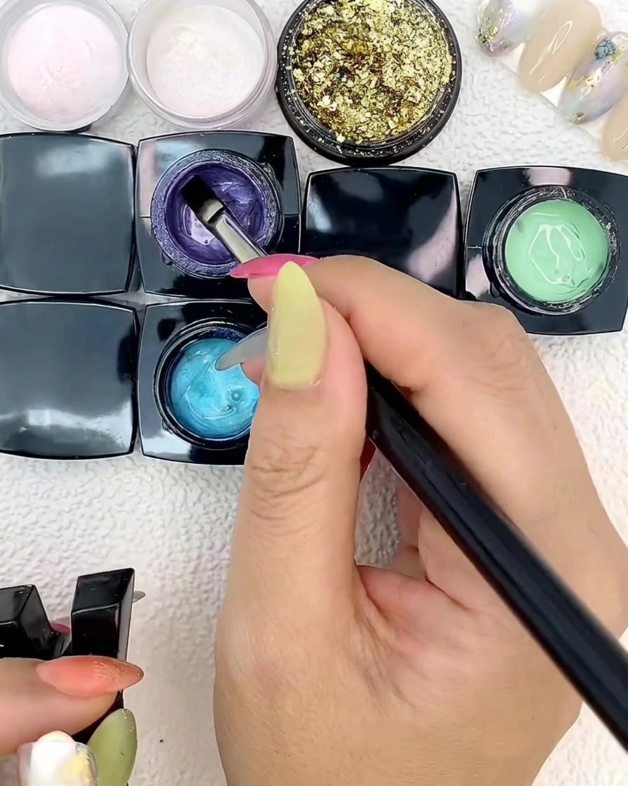 Ein flacher Nagelkunstpinsel trägt blaues Gel auf eine Nagelspitze auf.