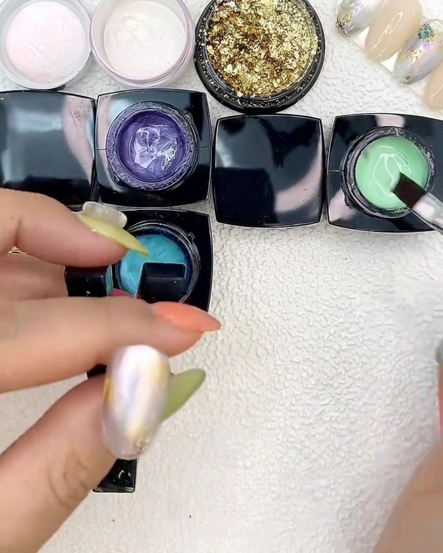 Das Auftragen von hellgrünem Gel neben blaue Flecken auf einer Nagelspitze mit einem flachen Pinsel.