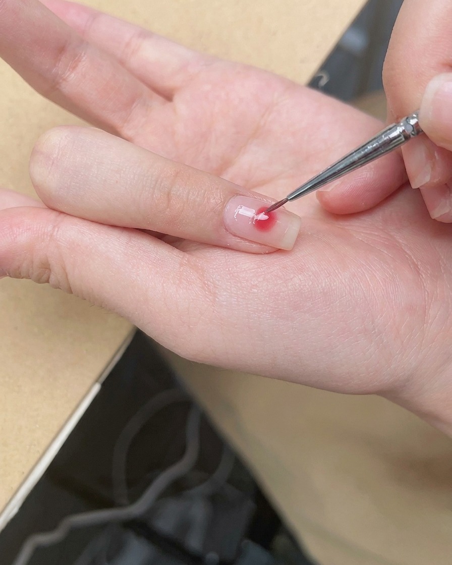 Ein feiner Pinsel verblendet die Ränder des rosa Punktes zu einem sanften Blush-Ombré.