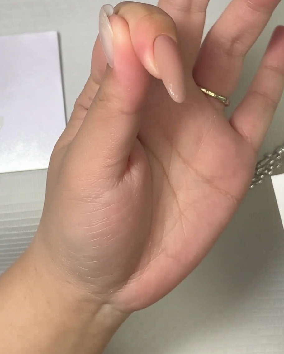 Ein Pinsel trägt einen matten Überlack auf einen neutralen Nagel auf.