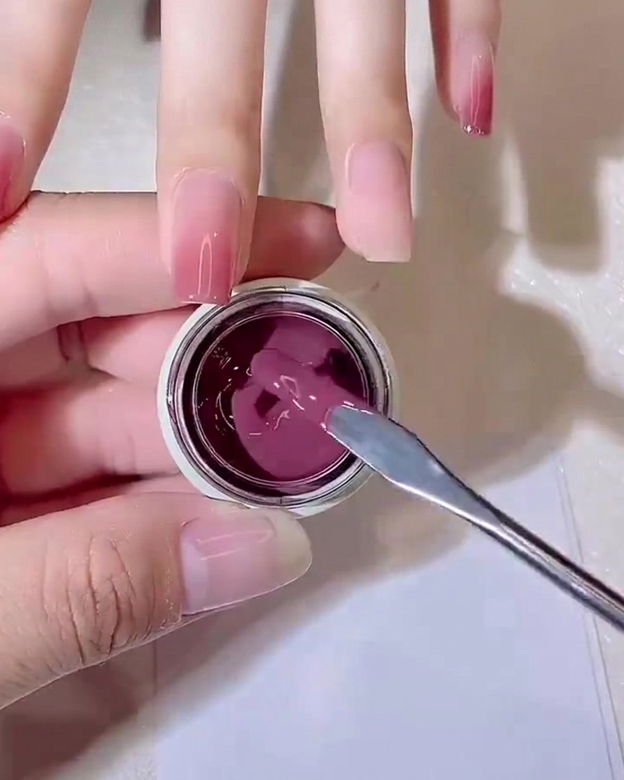 Ein Metallspatel hebt einen kleinen Klecks purpur-rosa Jelly-Gel aus einem kleinen Tiegel.