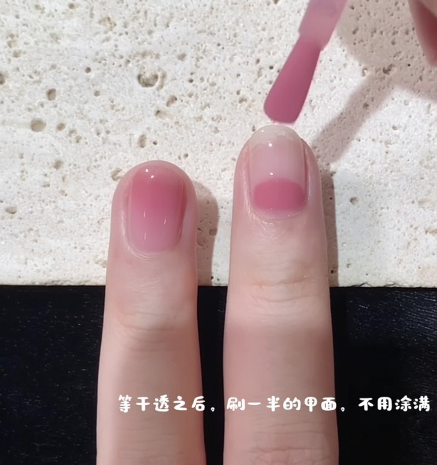 Ein Pinsel beginnt den Auftrag des rosa Lacks in der Nagelmitte, um den Verlaufseffekt zu starten.