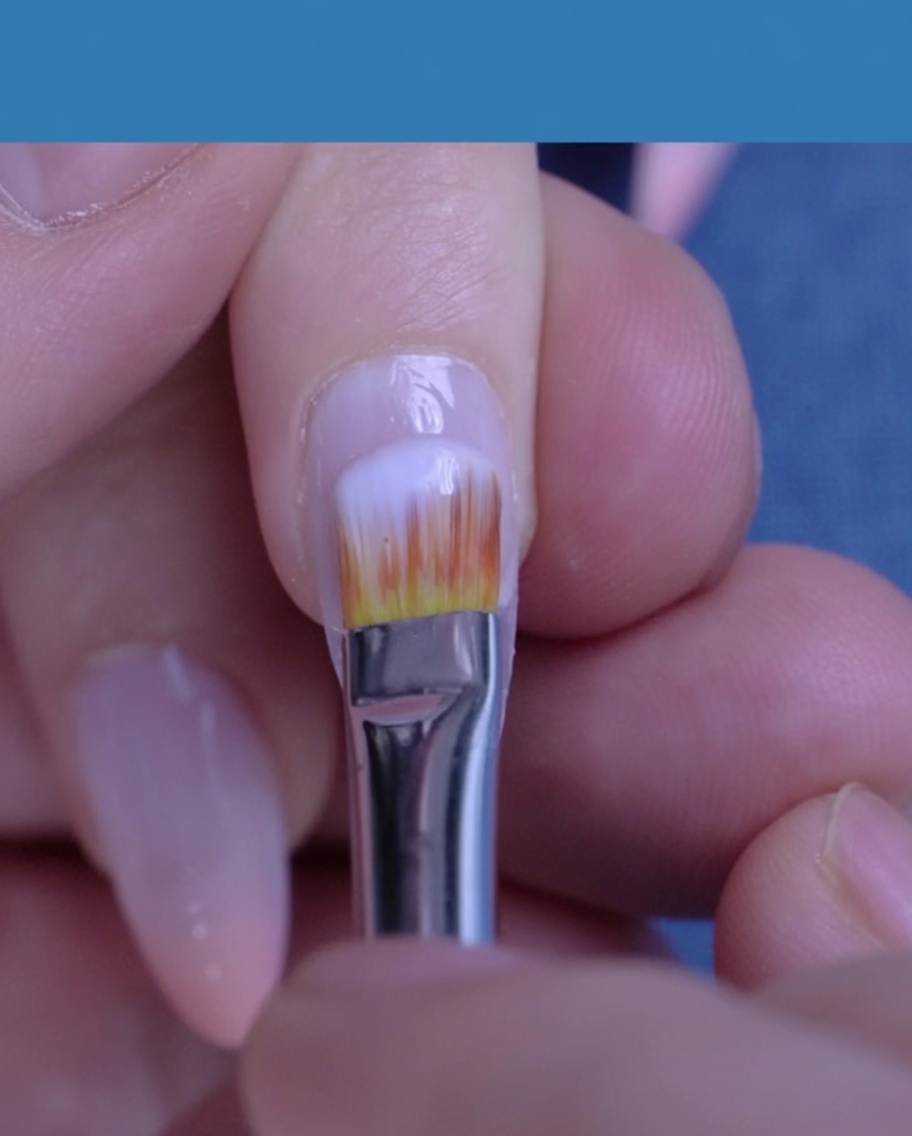 Ein Pinsel trägt ein transluzentes, milchig-weißes Gel über den gesamten Naturnagel auf.
