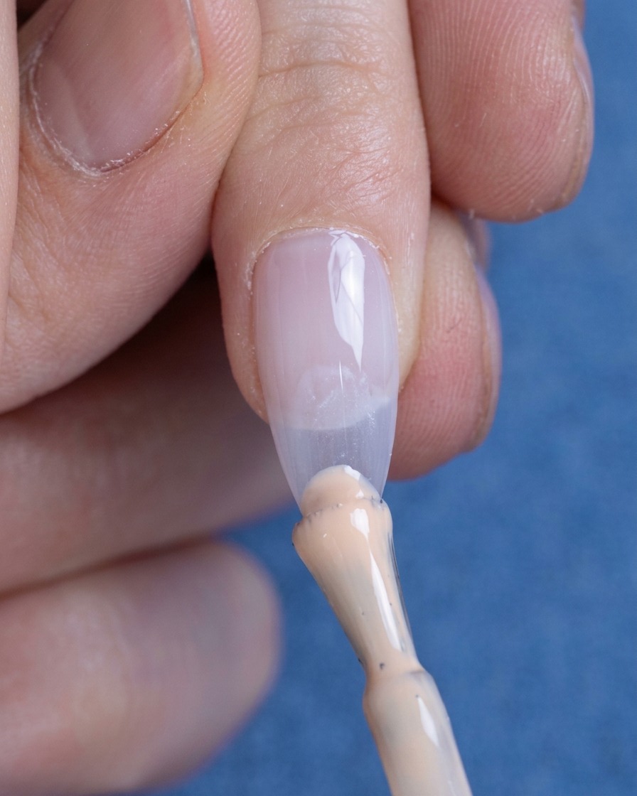 Ein kleiner Tropfen Nude-Gel wird auf die Nagelspitze aufgetragen.