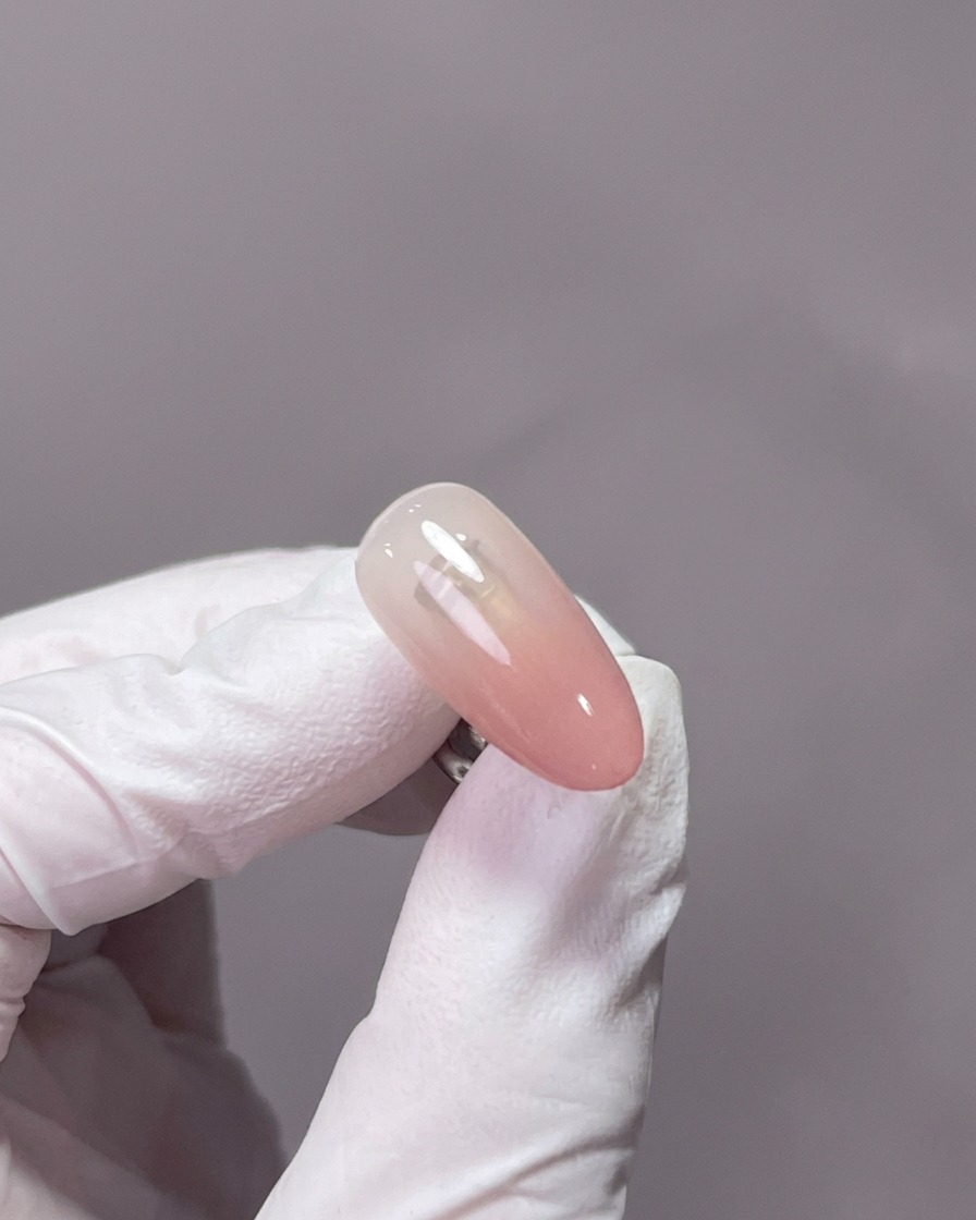 Eine Hand in einer professionellen UV/LED-Lampe, wobei die mit Gel bedeckten Nägel mittig unter dem Licht liegen.