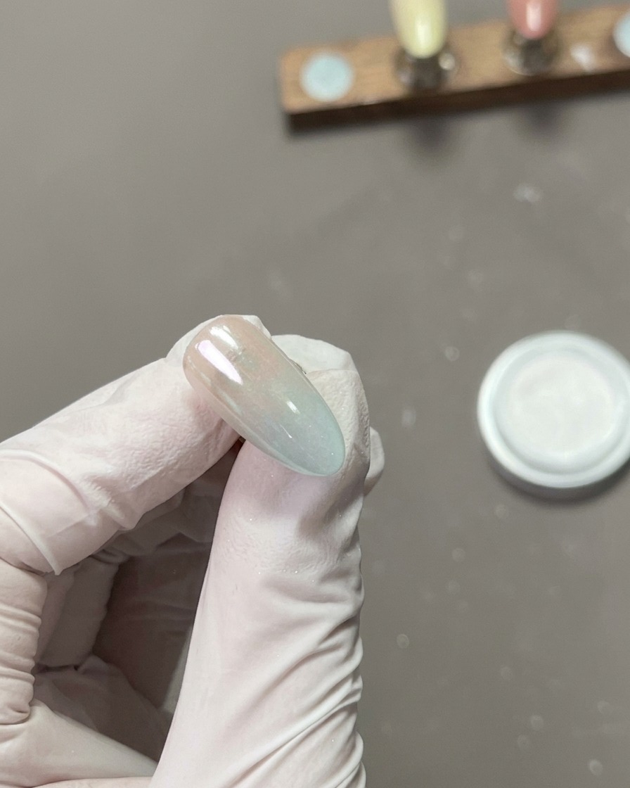 Ein Finger poliert die Oberfläche eines mit Chrom beschichteten Nagels, wodurch eine hochglänzende Spiegelreflexion entsteht.