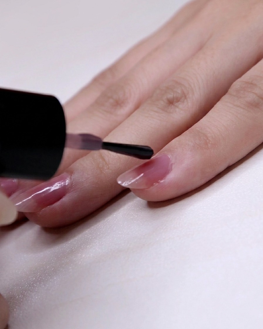Rosa Lack wird beginnend bei zwei Dritteln der Nagellänge bis zur Spitze des kleinen Fingers aufgetragen.