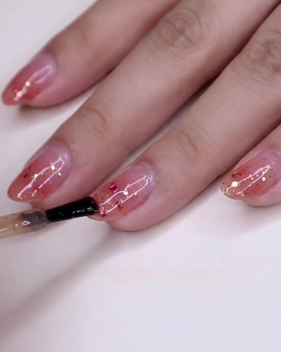 Ansicht der Hand mit noch feuchtem Glitzerlack, der über der rosa Gradienten-Basis trocknet.