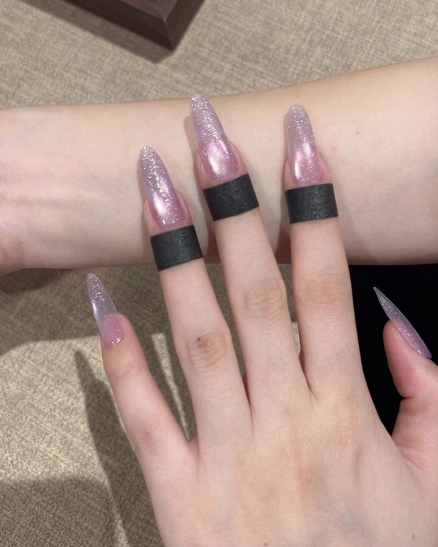 Ein Pinsel trägt schimmernden, violetten Cat-Eye-Gellack auf die gesamte Oberfläche des Nagels auf.