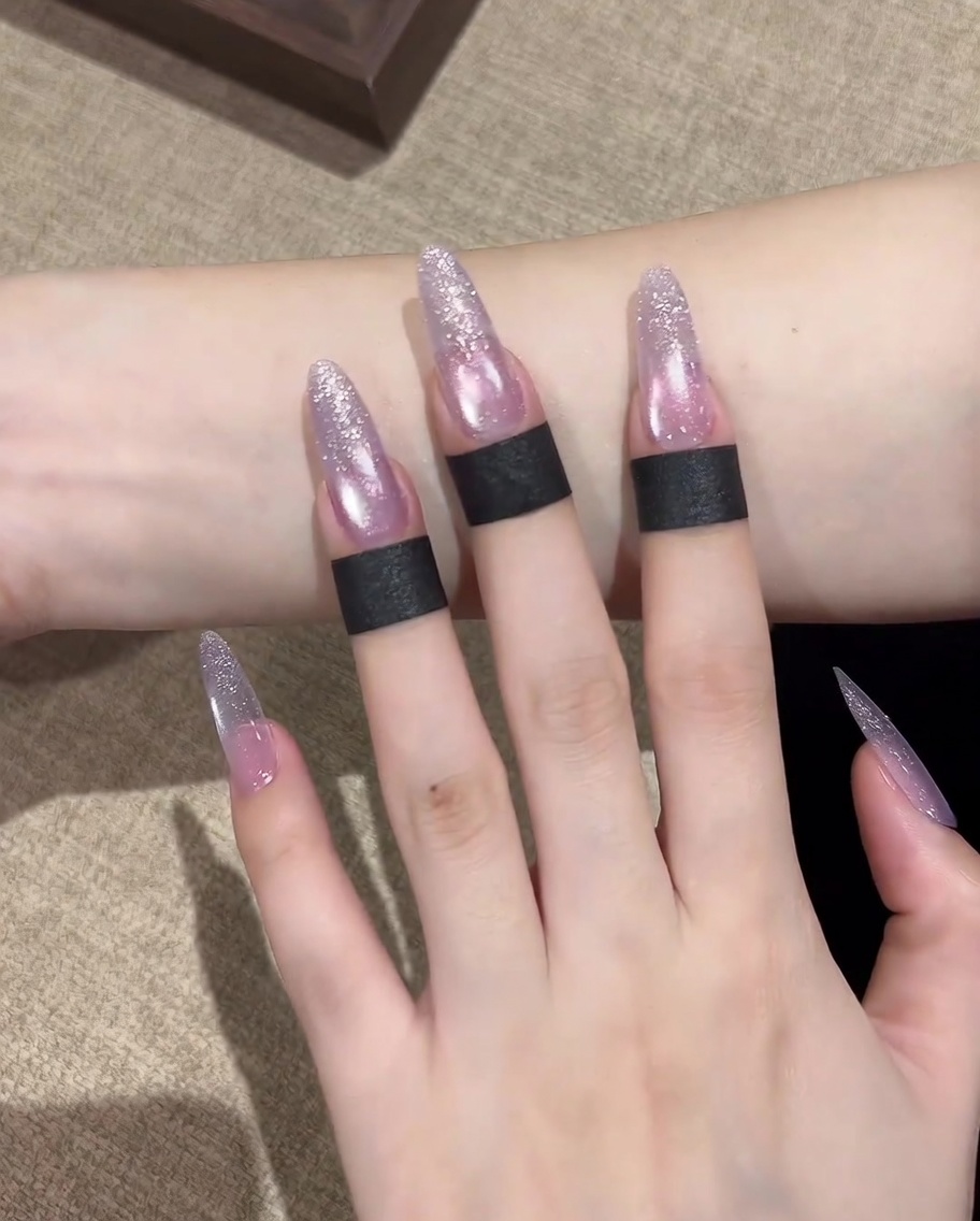 Nahaufnahme, die zeigt, wie der Magnet verwendet wird, um die schimmernden Partikel zu einem kreisförmigen Highlight in der Nagelmitte zu sammeln.
