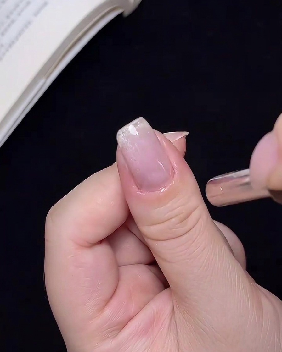 Ein starker Nagelmagnet wird nahe an einen Nagel gehalten, um die Cat-Eye-Schimmerpartikel zu verschieben.