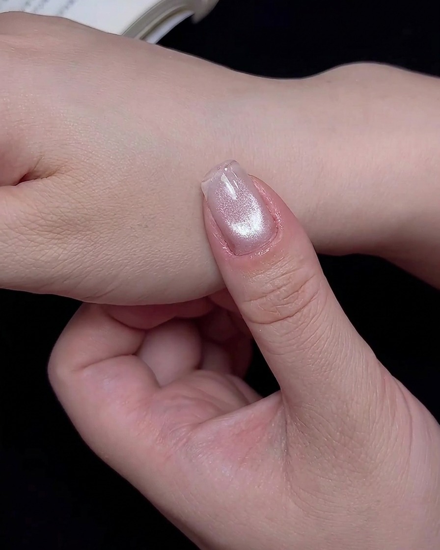 Ein Fingernagel wird zum Aushärten des frischen Cat-Eye-Designs in eine UV/LED-Lampe gelegt.