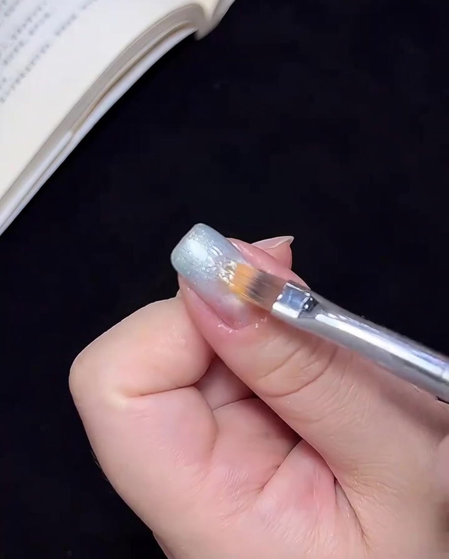 Ein Pinsel verblendet das blaue Gel zur Nagelmitte hin, um einen Ombré-Übergang zu erzeugen.