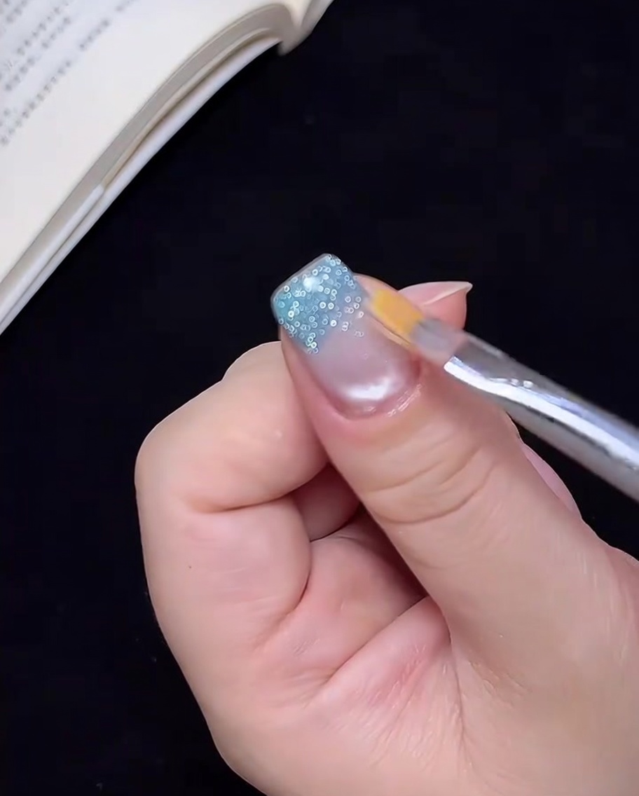 Ein sauberer Pinsel zieht das blaue Glitzergel leicht nach oben, um einen Ombré-Effekt zu erzeugen.