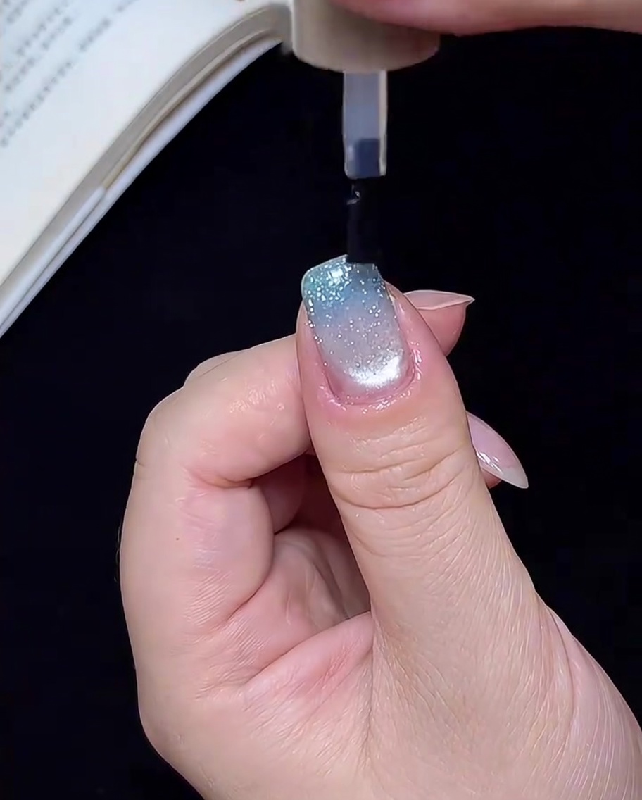 Eine Hand in einer UV/LED-Lampe, während die Nägel für den letzten Schritt unter dem Licht aushärten.