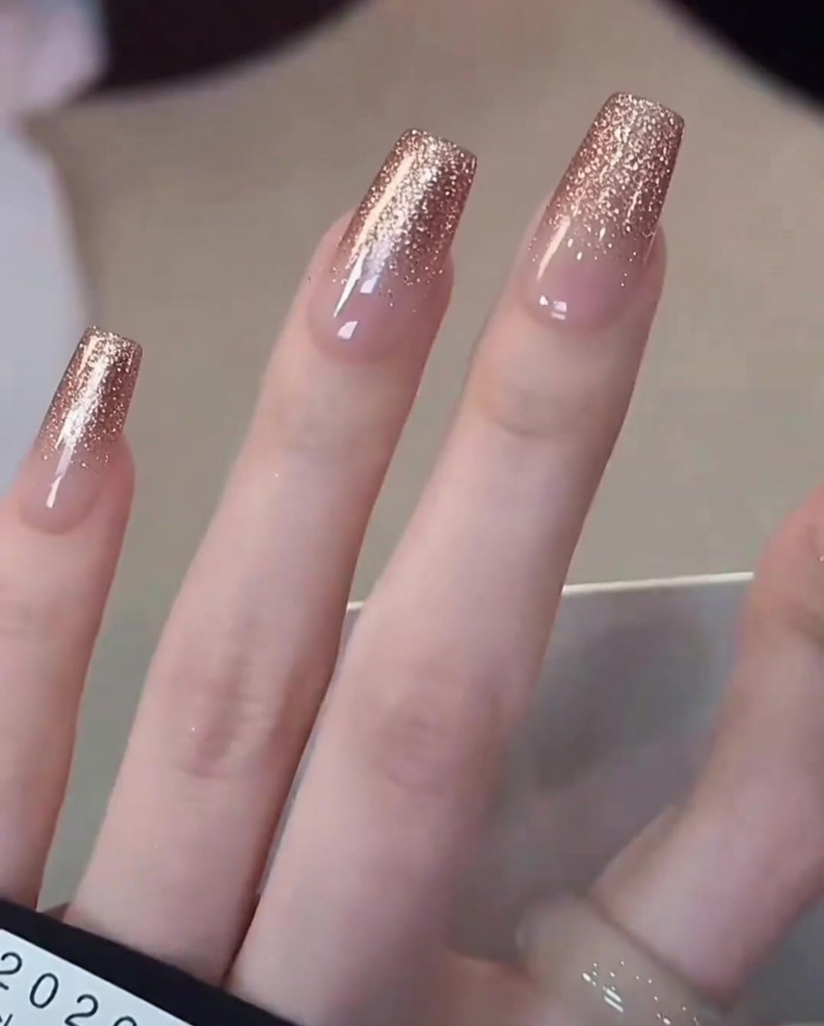 Nahaufnahme eines Pinsels, der milchig-weißen Gellack gezielt auf die Spitze eines Naturnagels aufträgt.