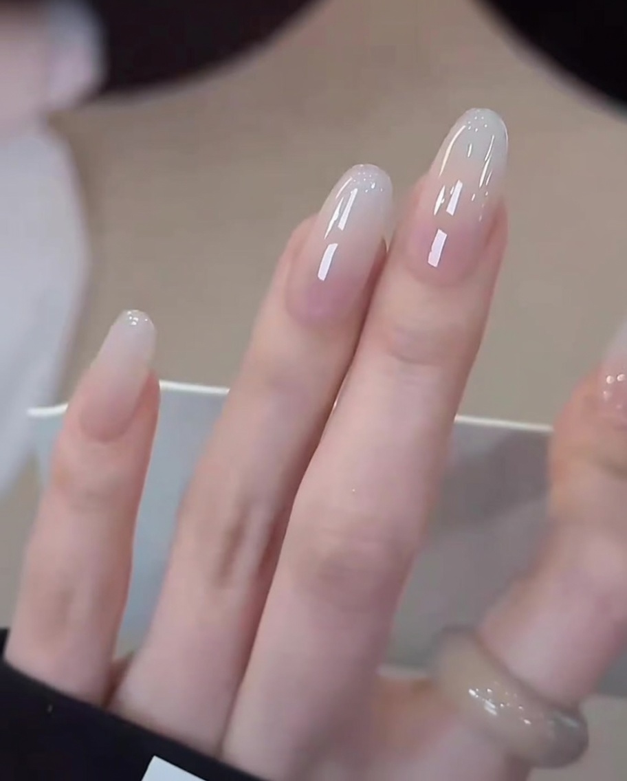 Nahaufnahme einer Hand mit fertigen Milky White Gradient Nails in einer professionellen UV/LED-Lampe für die finale Aushärtung.