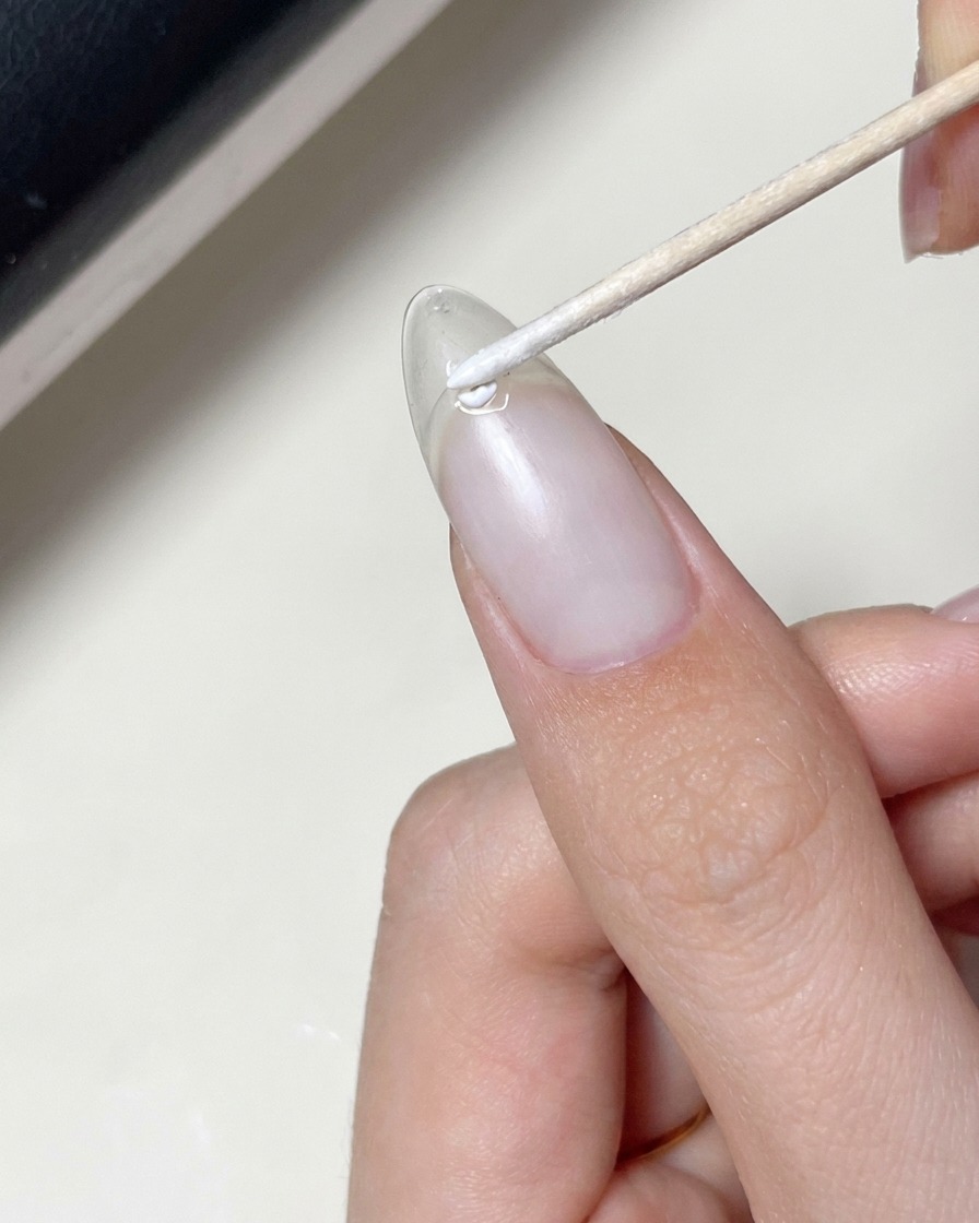Ein Pinsel trägt eine Schicht klares Gel über einen Nagel mit platziertem Stern-Aufkleber auf.