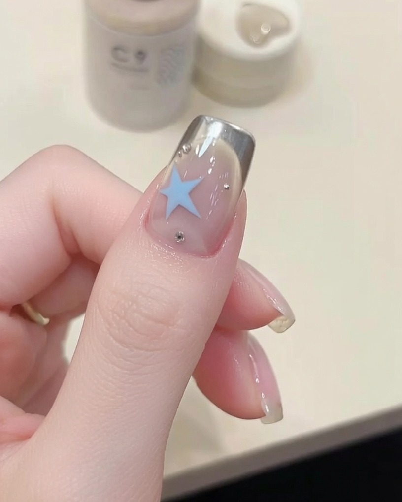 Ein Nagelpinsel trägt klaren, glänzenden Überlack auf einen manikürten Nagel auf.