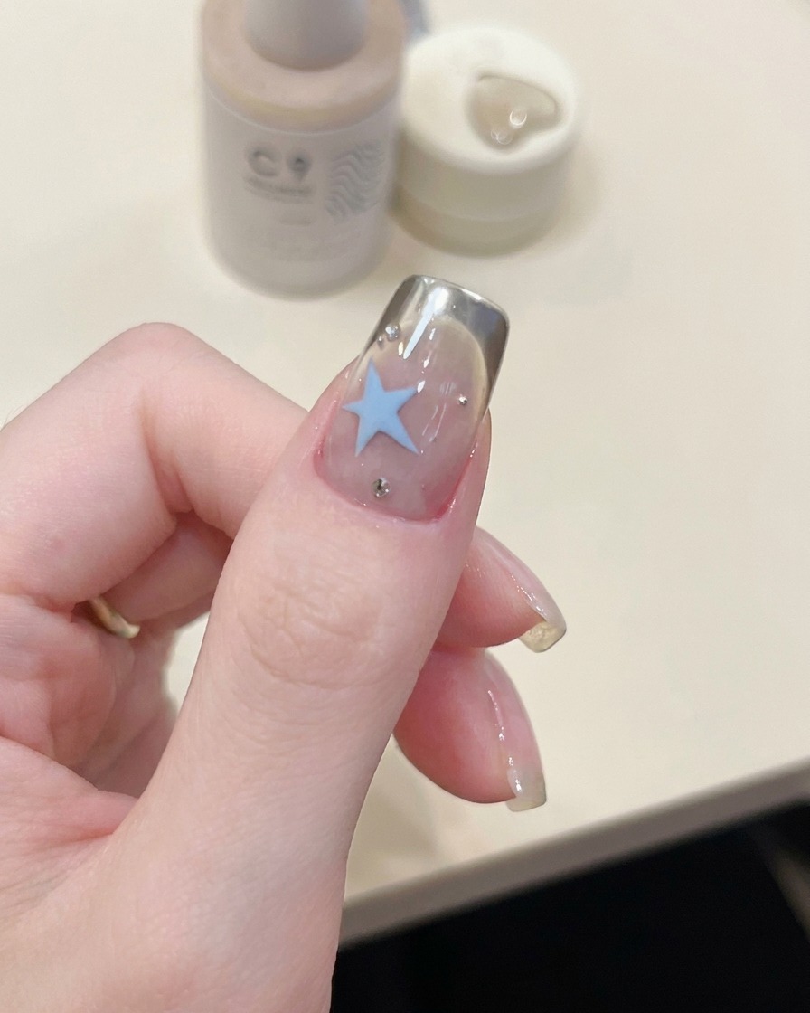 Eine Pinzette platziert eine geschwungene French-Tip-Schablone auf der Nagelspitze.