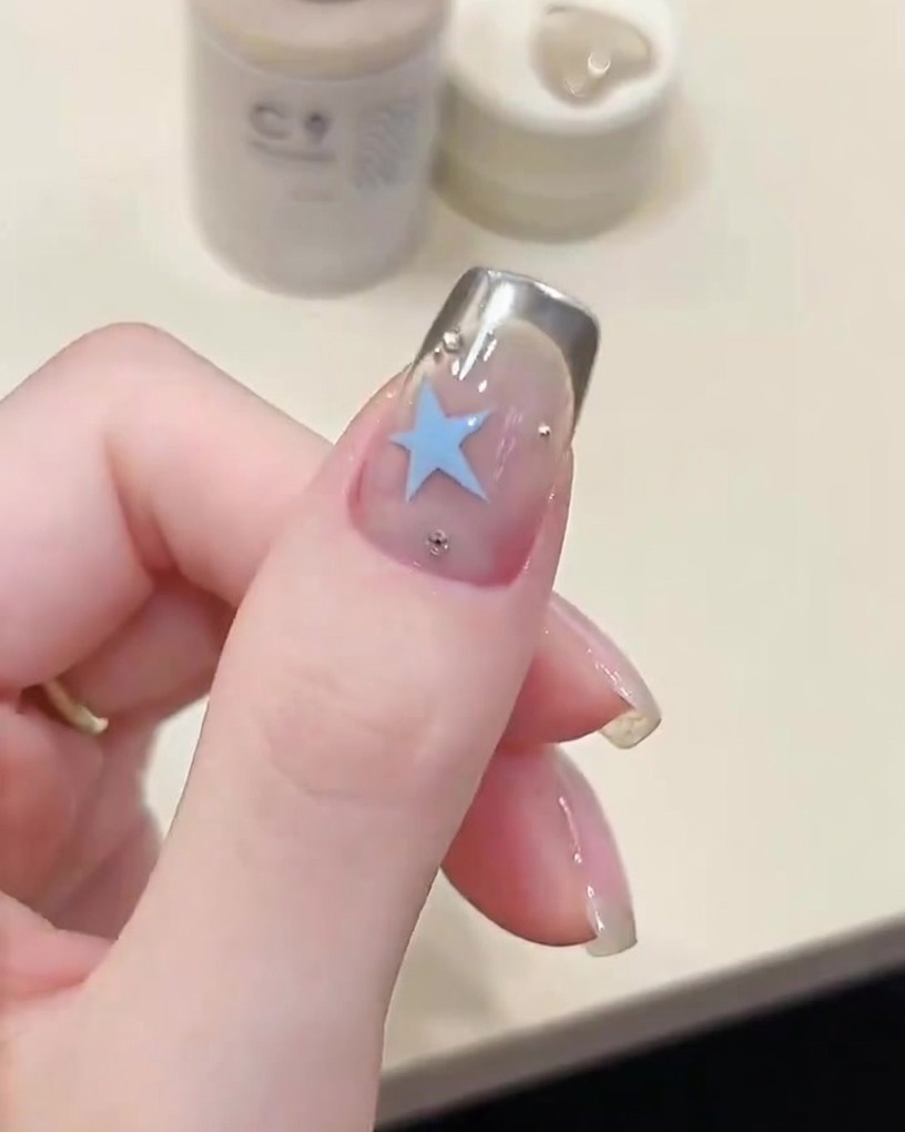 Eine Pinzette zieht vorsichtig die French-Tip-Schablone ab und enthüllt eine scharfe silberne Chrome-Linie.