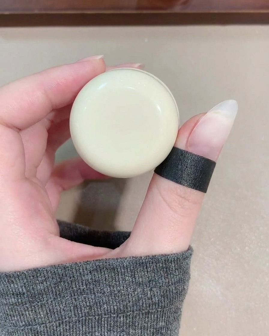 Ein Gel-Pinsel trägt transparentes, schimmerndes blaues Cat-Eye-Gel auf einen Fingernagel auf.