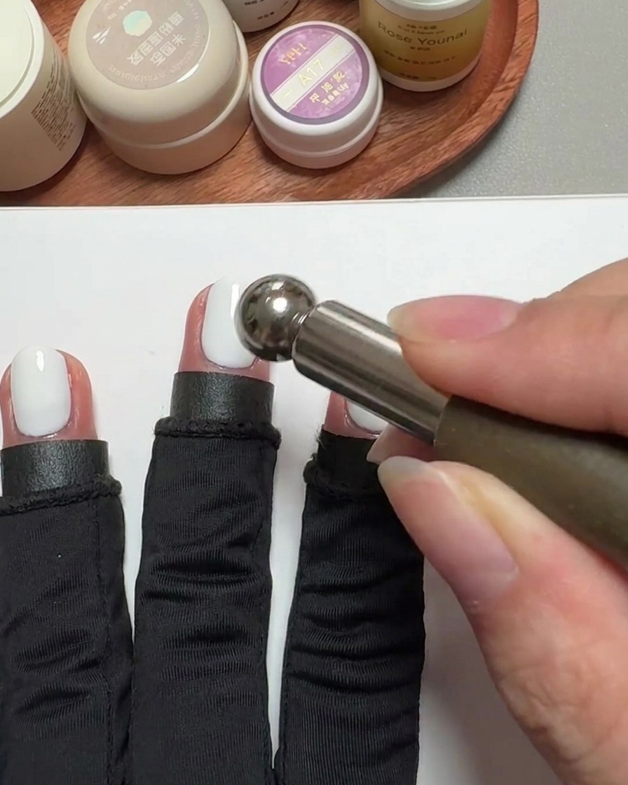 Nahaufnahme eines zylindrischen Magnetwerkzeugs, das über einem mit Gel überzogenen Fingernagel schwebt, um den Cat-Eye-Effekt zu erzeugen.