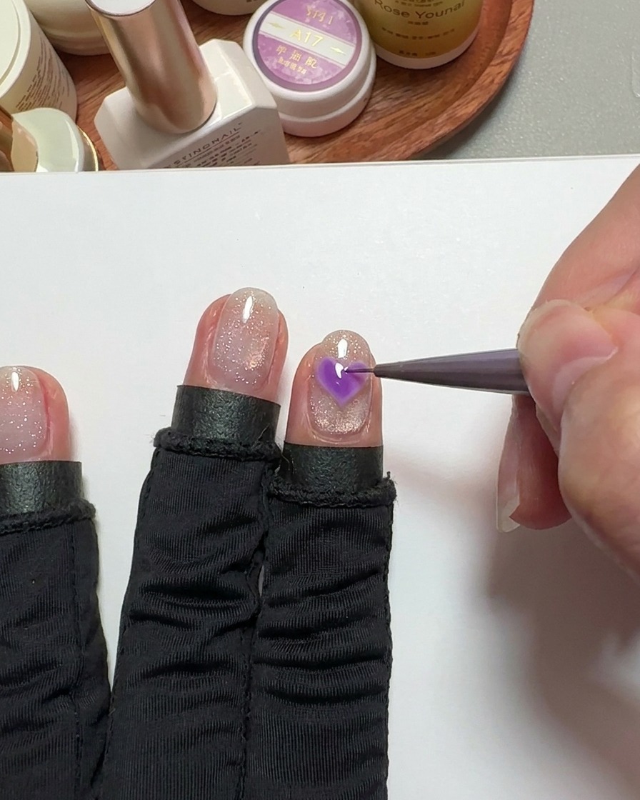 Ein Detailpinsel füllt ein Herz auf dem Nagel mit pinkem Gel aus.
