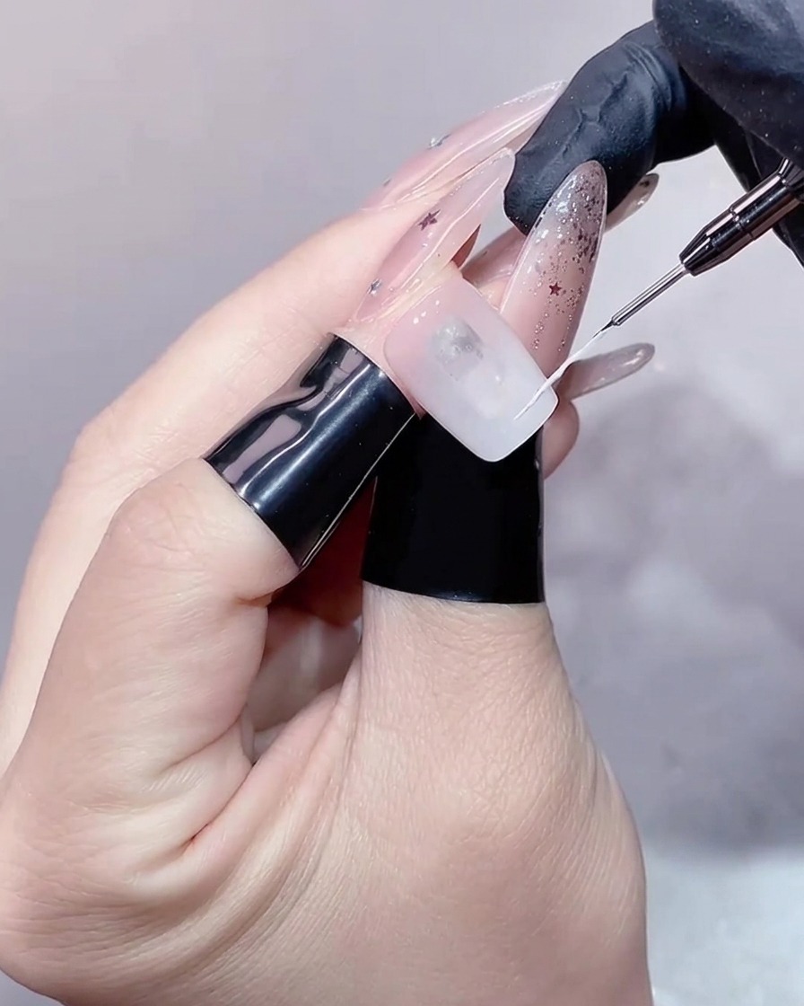 Ein feiner Liner-Pinsel zeichnet eine zarte weiße Linie für den French-Look.