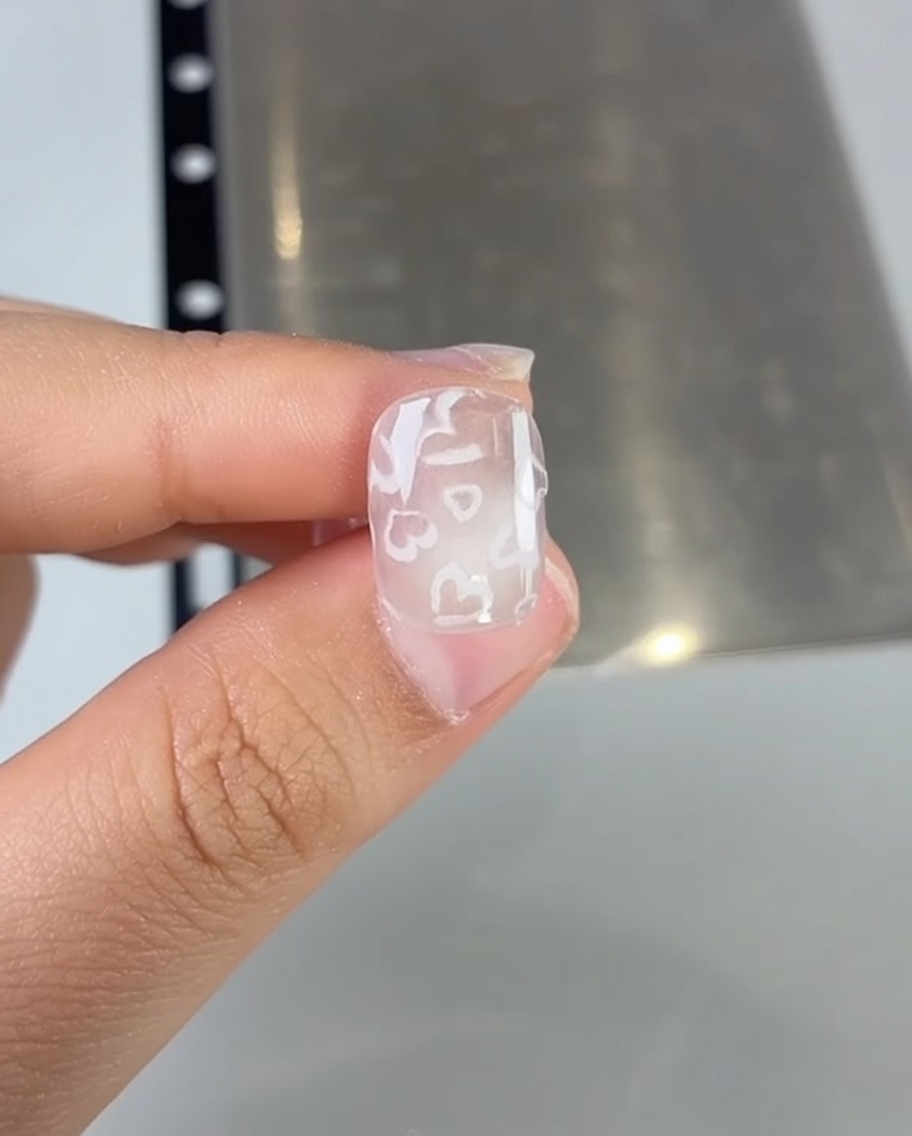 Nahaufnahme eines Nagelpensele, der rosa Gellack auf einen Nagel aufträgt.