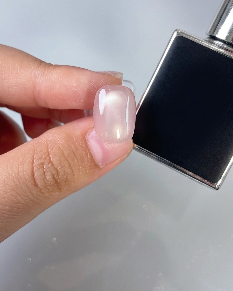Ein Nagelpense, der eine dünne Schicht klaren Überlack über einen rosa Nagel aufträgt.