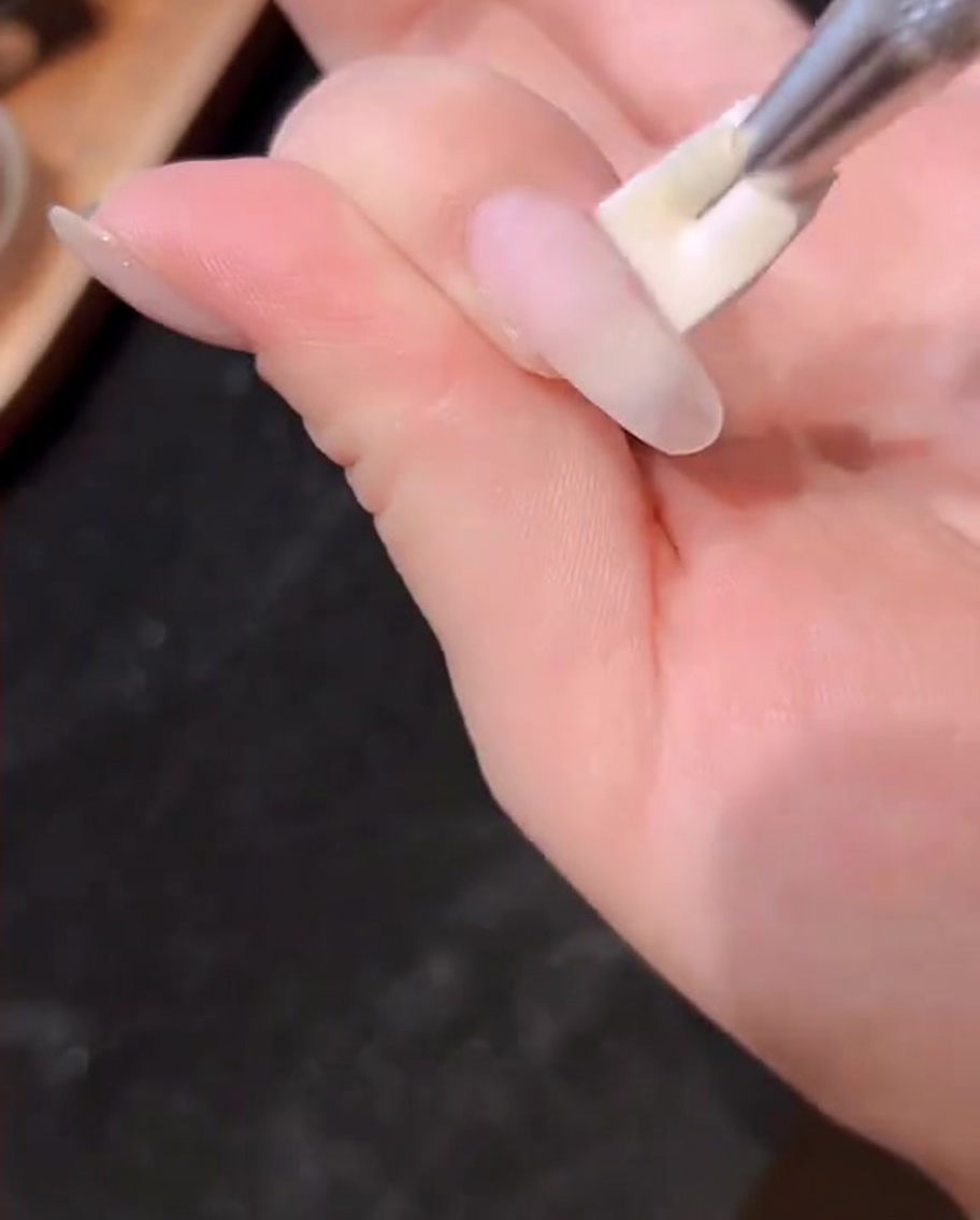 Eine Hand ruht in einer professionellen UV/LED-Lampe während der Aushärtung.