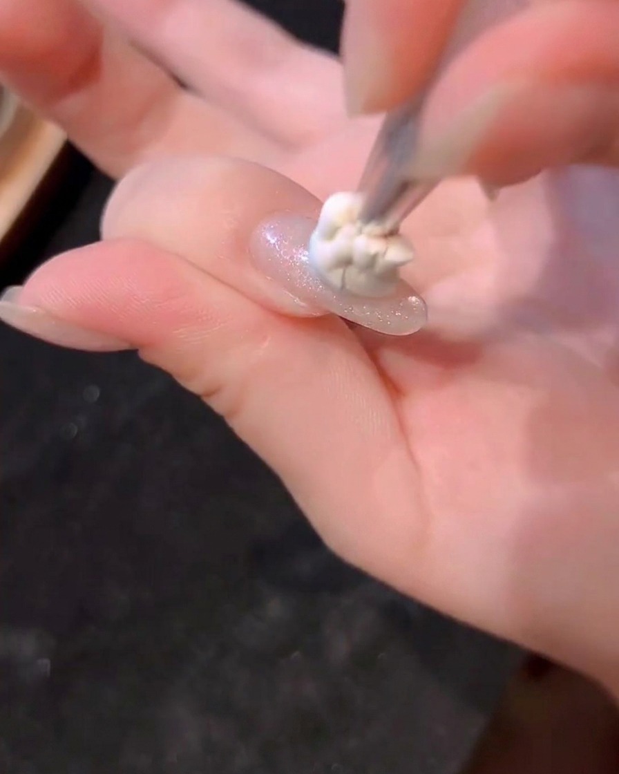 Ein kleiner Punkt blaues Gel wird mit einem Pinsel in die Nagelmitte getupft.