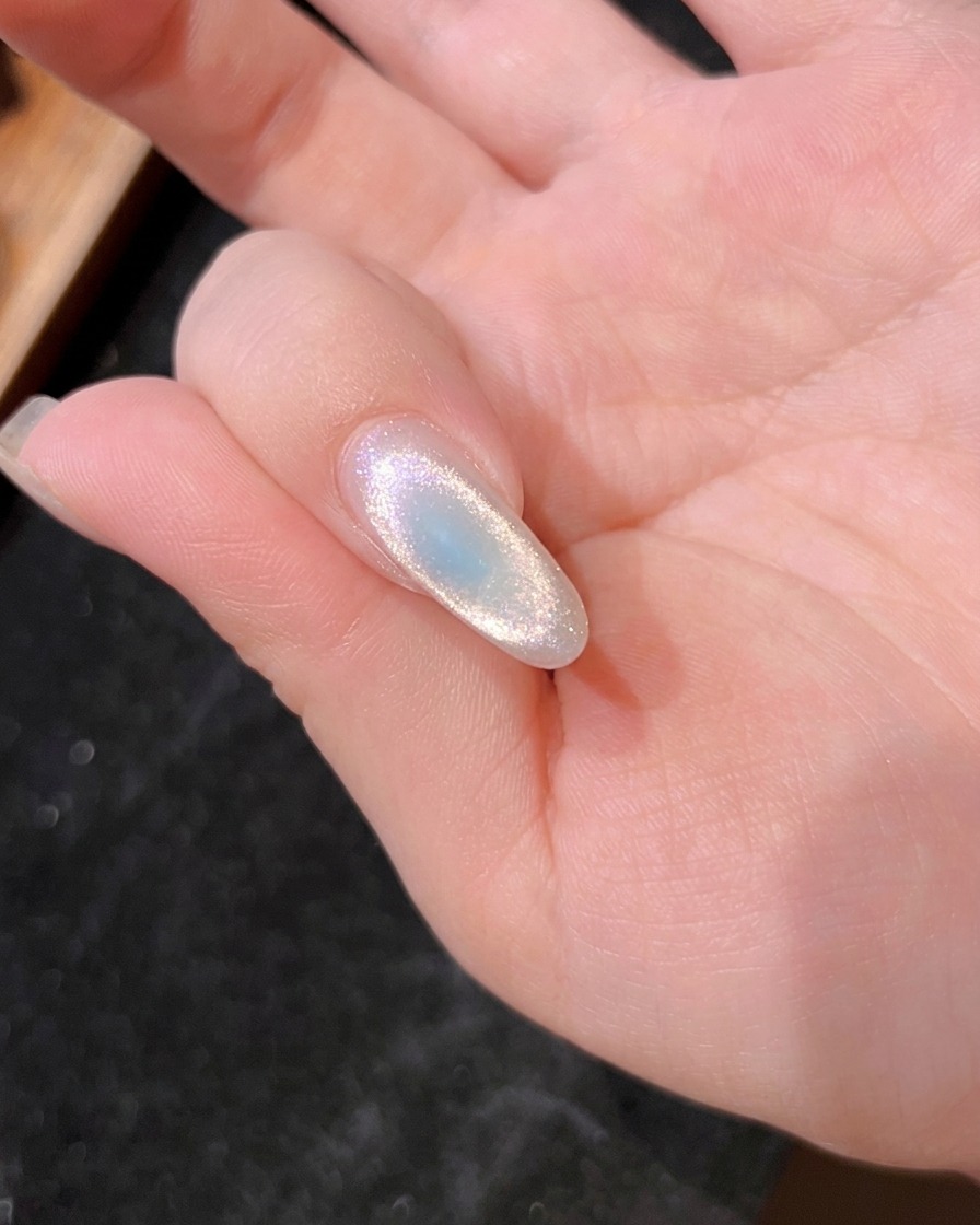 Nahaufnahme eines Nagels unter der UV-Lampe bei der Aushärtung der zweiten blauen Schicht.