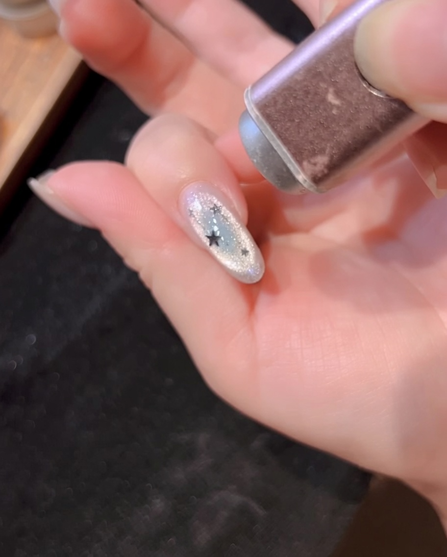 Eine Hand-UV-Lampe härtet den mit Sternen dekorierten Nagel aus.