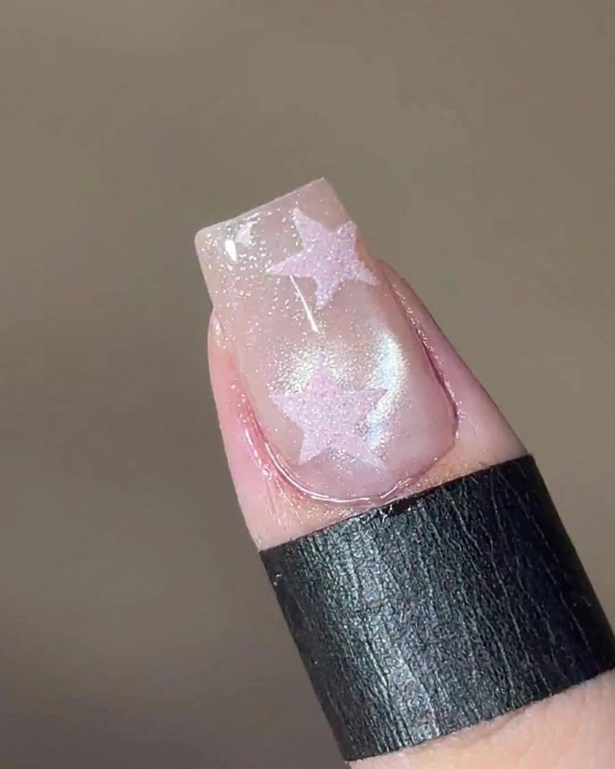 Ein Magnetwerkzeug wird über den Nagel gehalten, wodurch die schimmernden Partikel im Gel einen glasartigen Lichtpunkt bilden.