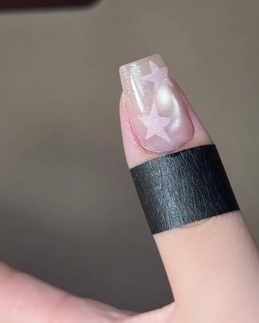 Finger härten ein Stern-Nageldesign unter einer professionellen UV-Nagellampe.